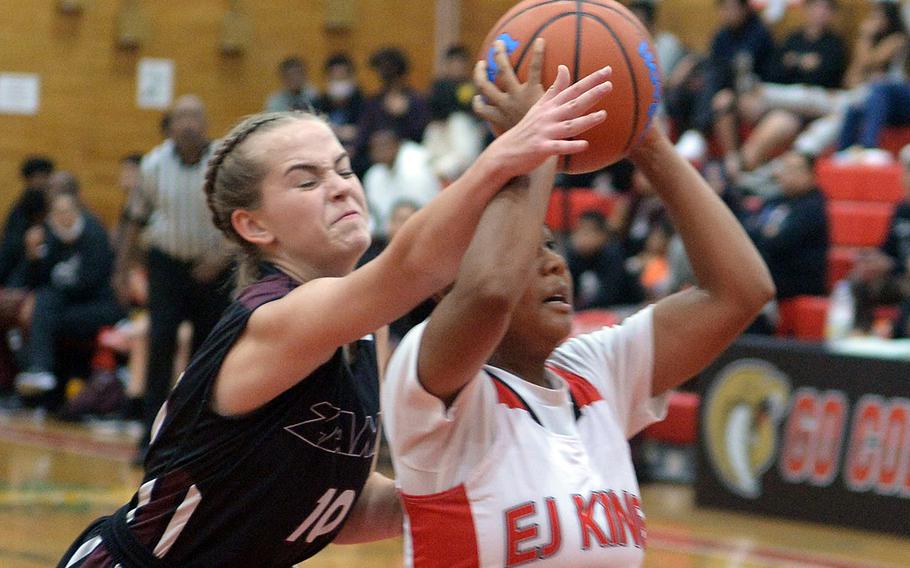 Zama's Olivia Parish tries to block a shot by E.J. King's Moa Best during Friday's DODEA-Japan season-opening basketball game. The Cobras won 69-33.