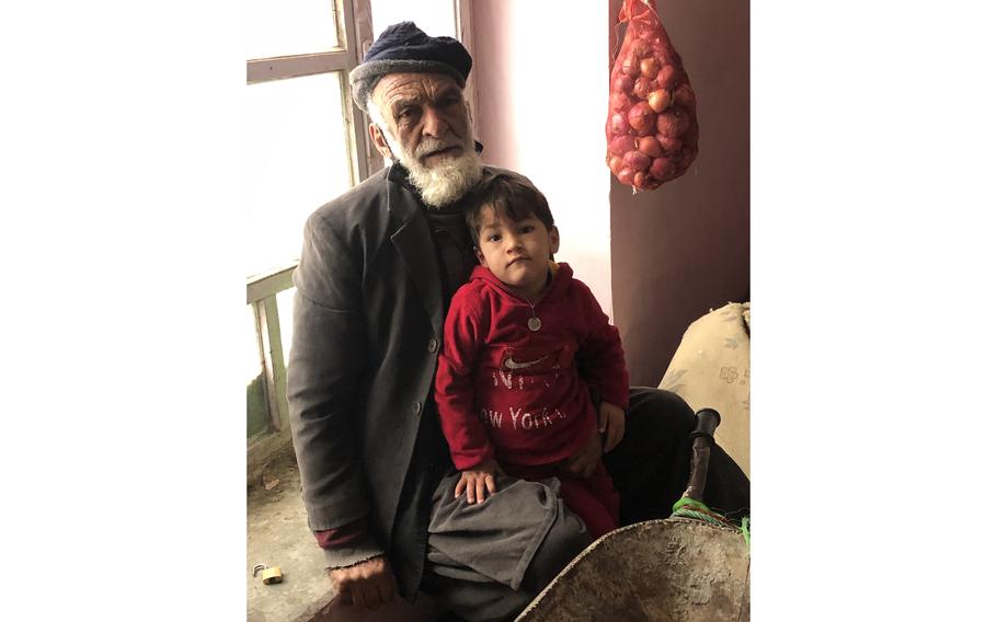 Abdul Hadi sits with his grandson Yasin and the wheelbarrow he pushes for hire in Kabul, Afghanistan, on Jan. 4, 2022. 
