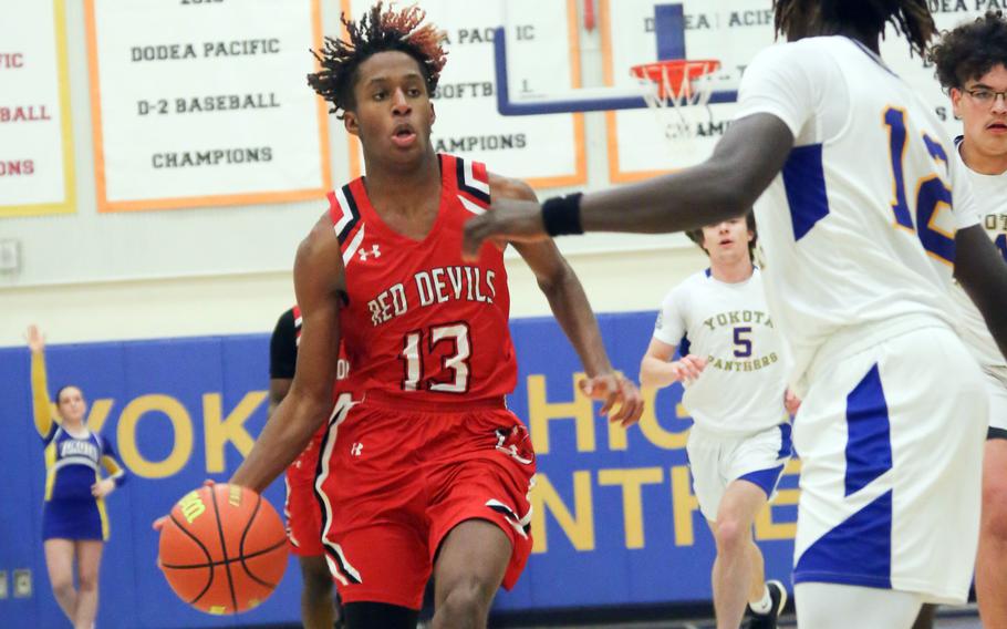 Nile C. Kinnick's Jaelin White dribbles against Yokota's Jai Bailey during Tuesday's DODEA-Japan/Kanto Plain boys basketball game. The Red Devils won 73-61 despite Bailey scoring 30 points for the Panthers.