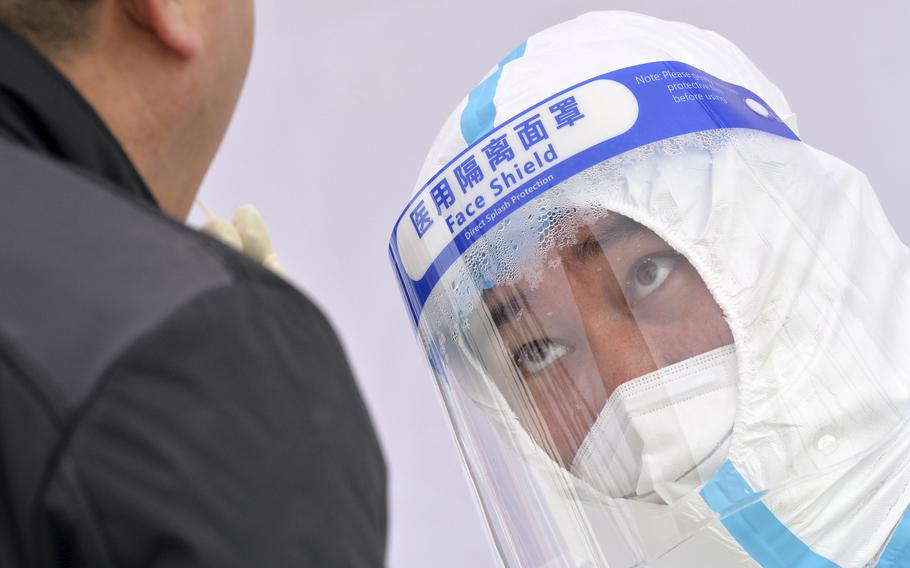 A medical worker’s face shield fogs up as he takes a sample from a resident during a second round of COVID-19 testing in China’s Tianjin Municipality on Wednesday, Jan. 12, 2022. 