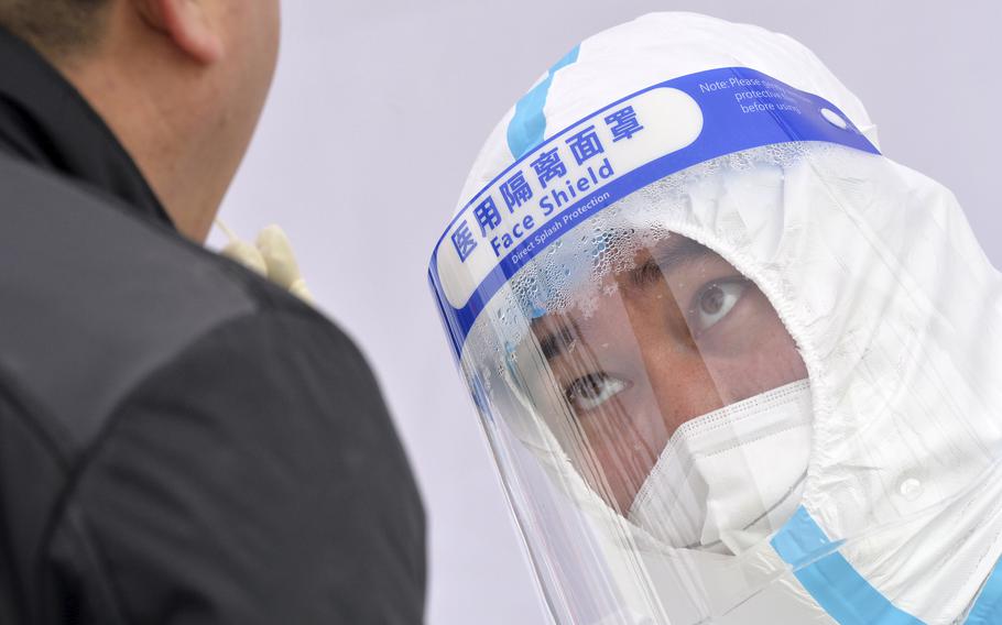 A medical worker’s face shield fogs up as he takes a sample from a resident during a second round of COVID-19 testing in China’s Tianjin Municipality on Wednesday, Jan. 12, 2022.
