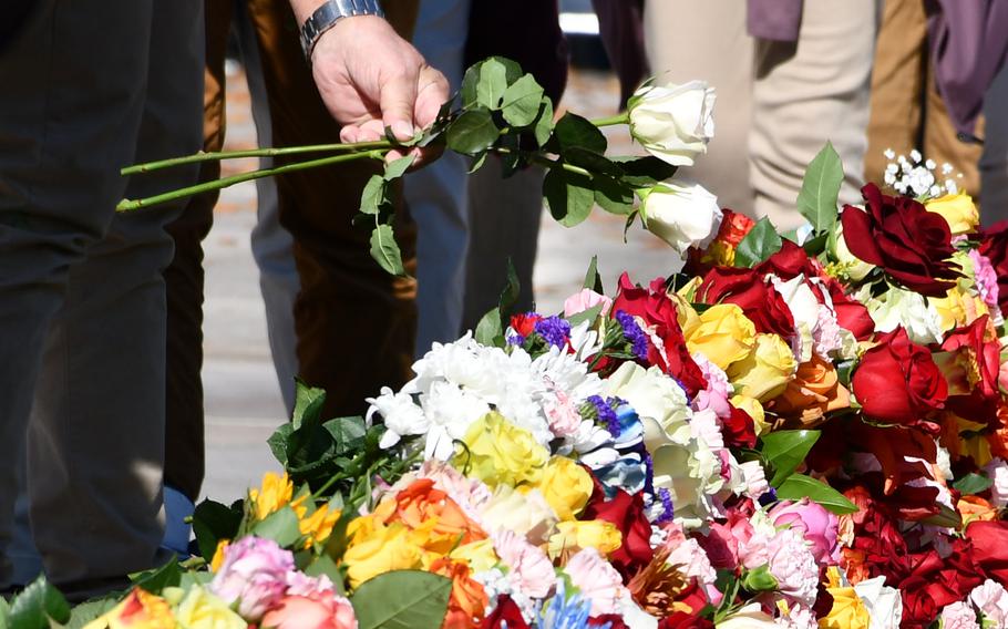 A visitor drops white roses onto a heap of flowers at the Tomb of the Unknown Soldier on Wednesday, Nov. 10, 2021. For two days, Arlington National Cemetery allowed visitors to approach the tomb and place flowers.