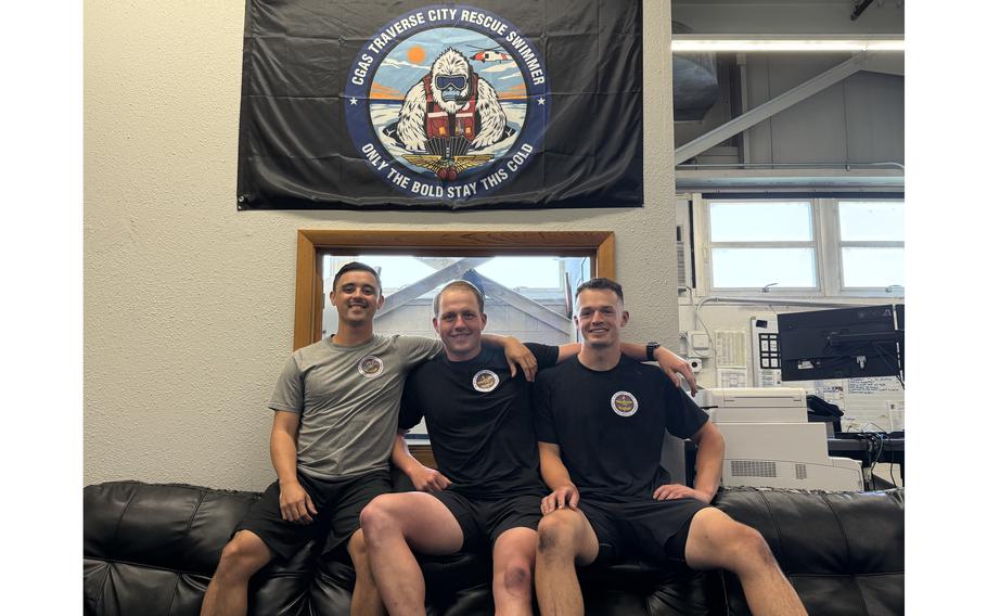Three Coast Guardsmen pose embrace each other for a photo.