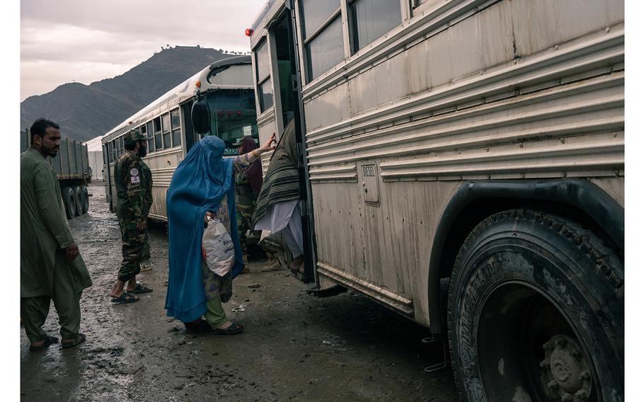At the Torkham border crossing in Afghanistan on Nov. 9, 2023, a woman steps onto a bus heading to a camp for returnees who have been forced out of Pakistan. 