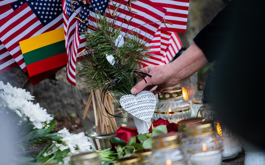 A person places a heart on a memorial with candles and American flags.