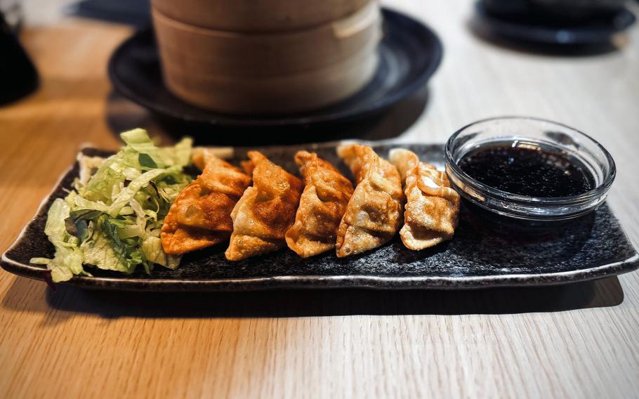 A plate of gyoza sits on a table at a Japanese restaurant.