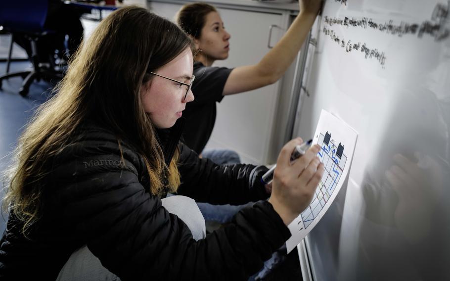 Gwyn Cedarholm, left, and Julia Adkins work on the algorithm of their robot at Ramstein High School at Ramstein Air Base, Germany, March 18, 2024. The robot has to move under remote control and autonomously to garner the most points. 