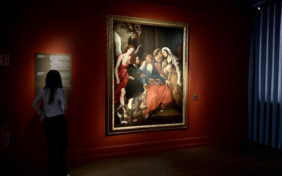 A museum visitor looks at a painting on display.