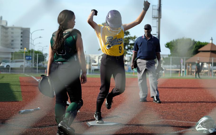 Kadena's Jessica Petruff celebrates as she touches home plate following an inside-the-park home run, and runs past a glum-looking Kubasaki catcher Mia Vedsted.