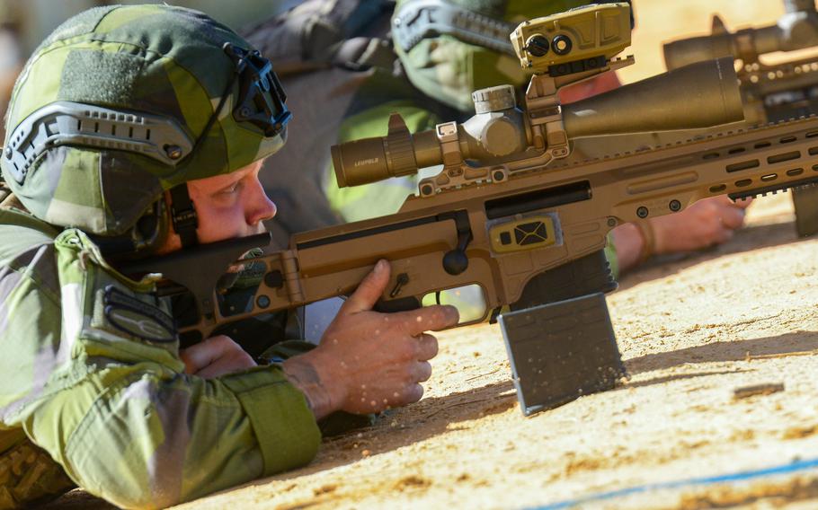 A soldier, lying on the ground, aims his rifle.