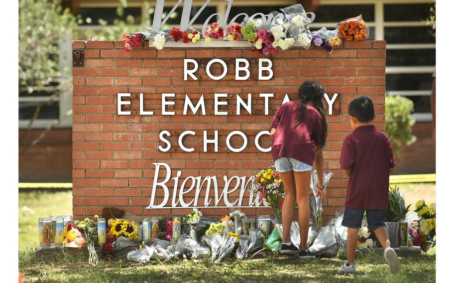 Family members who lost a sibling place flowers outside Robb Elementary School in Uvalde, Texas, on Wednesday, May 25, 2022. 