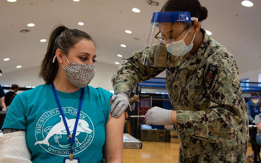 U.S. Navy Seaman Janasia Spotson, a hospital corpsman, administers the COVID-19 vaccine to Andrea Hunt, a teacher's aide, in Yokosuka, Japan, March 19, 2021. Department of Defense Education Activity workers are required to be fully vaccinated or file for an exemption to fulfill a Pentagon directive. 