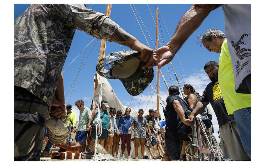A crew of Hawaiians joins hands in prayer after delivering a boatload of supplies for Lahaina fire victims at Maalaea Harbor, Aug. 14, 2023, Maui, Hawaii. 