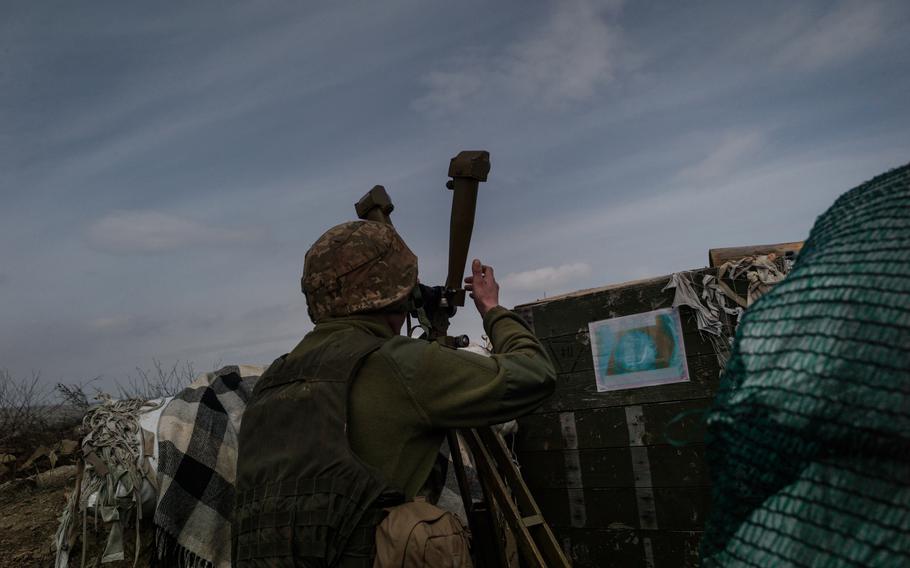 A soldier looks through a periscope. 