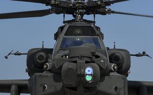 A close up of a black helicopter against a bright blue sky. 