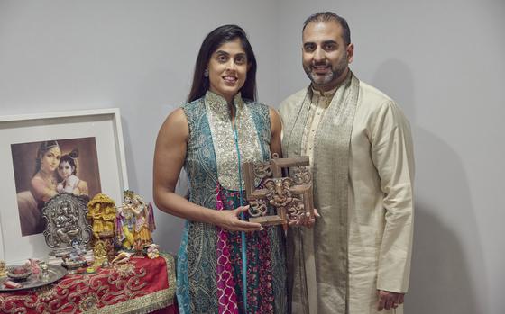 Sheetal Deo and her husband, Sanmeet Deo, hold a Hindu swastika symbol in their home in Syosset, N.Y., on Sunday, Nov. 13, 2022. Hindus, Buddhists and Native Americans are trying to rehabilitate the swastika, a symbol of peace and prosperity, and to restore it to a place of sanctity in their faiths. (AP Photo/Andres Kudacki)