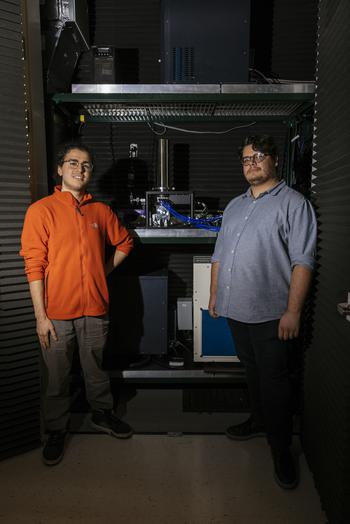 Graduate students Cyrus Zeledon, left, and Grant Smith pose for a portrait in front of a superconducting nanowire single-photon detector at the quantum computing lab of University of Chicago's Eckhardt Research Center on Oct. 4, 2022.