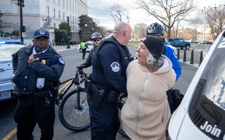 Officers take Micki Witthoeft, the mother of Ashli Babbitt, by the arm after she refused police warnings to move from the street onto the sidewalk. 