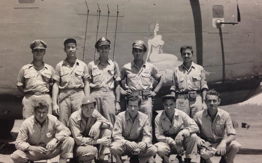 An Air Force crew poses for a photo in front of a bomber in a black and white photo.