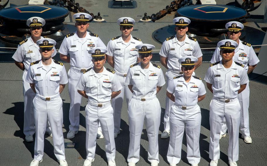 Sailors pose aboard the amphibious transport dock ship USS Arlington after qualifying as surface warfare officers, Oct. 2, 2022.