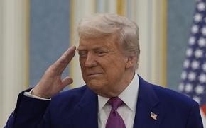 President Donald Trump wearing a blue suit salutes.