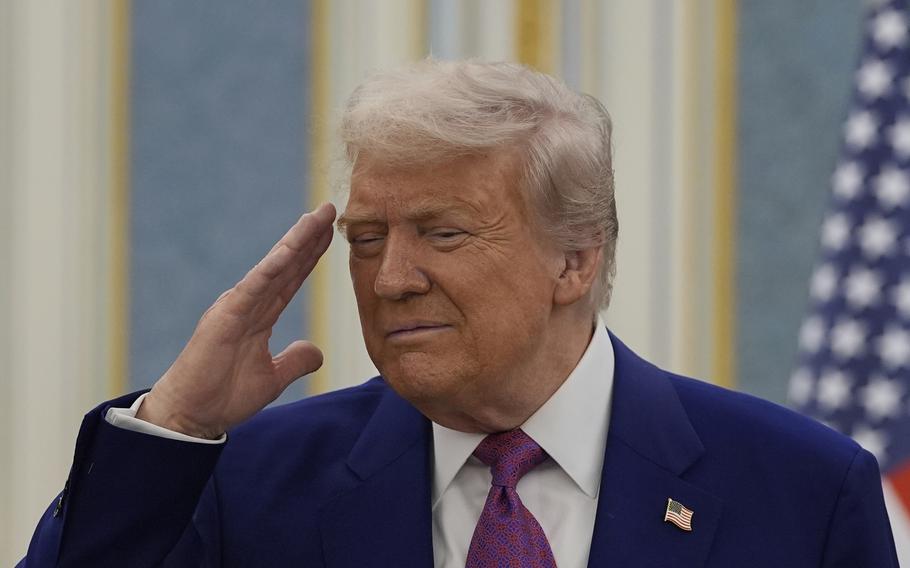 President Donald Trump wearing a blue suit salutes.