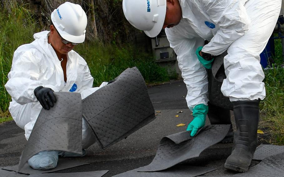 Navy contractors place absorbent mats at the site of a spill of toxic firefighting foam at the Red Hill underground fuel storage facility on the outskirts of Honolulu, Hawaii, Tuesday, Nov. 29, 2022.