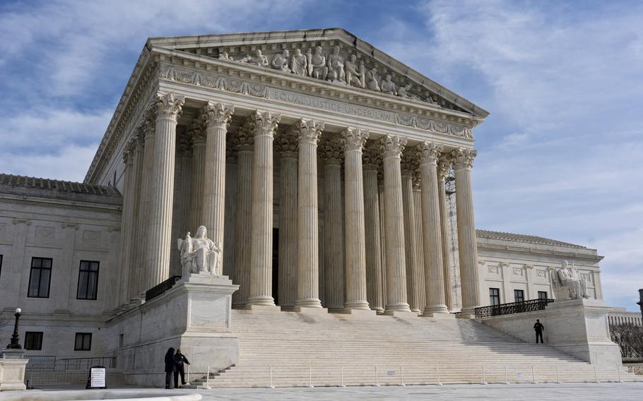 A street-level view of the front of the U.S. Supreme Court building with white stone columns atop white stone steps.