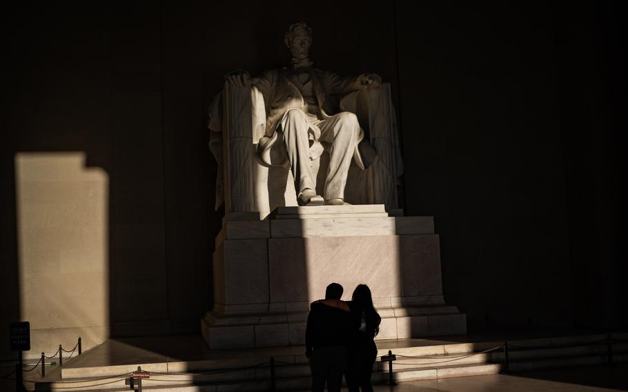 A couple takes in the statue of Abraham Lincoln as the morning light starts to shine on May 18, 2022. 