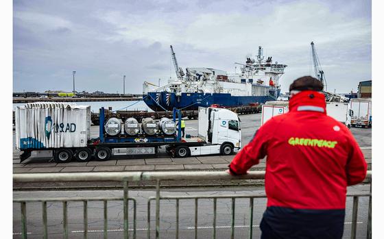 A Greenpeace activist observes the unloading of several cylinders of uranium from Russia at the port of Dunkirk, France, on March 20, 2023. (Sameer Al-Doumy/AFP/Getty Images/TNS)