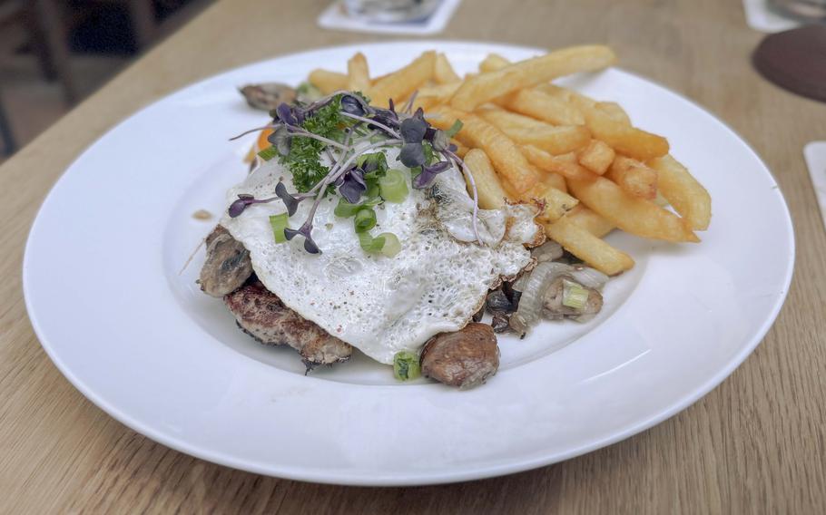 A pork steak topped with mushrooms, bacon, onions and a fried egg..