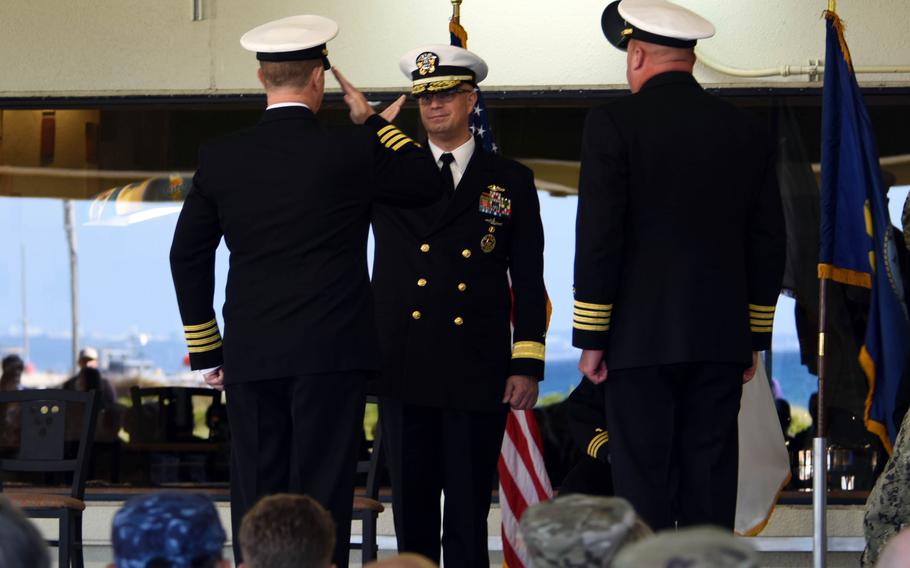 Rear Adm. Carl Lahti, center, commander of Navy Region Japan, salutes the outgoing leader of Fleet Activities Okinawa, Capt. Scott Hardy, during a change-of-command ceremony at White Beach Naval Facility, Thursday, Dec. 16, 2021. 