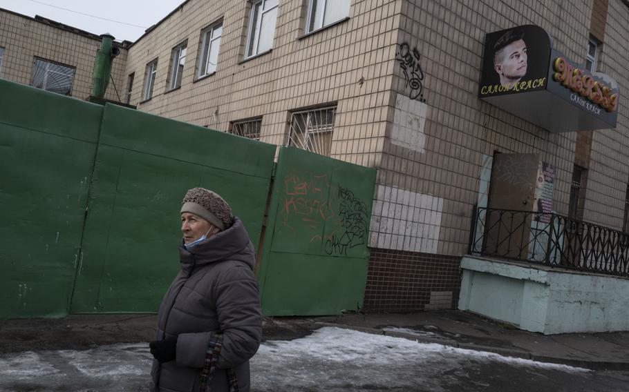 A woman walks past a metal gate that opens to a bunker in Kyiv. 
