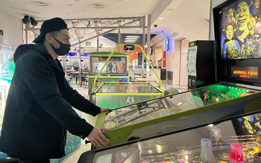 Airman John Cedrick, of San Diego, wears a mask while playing pinball at the Tomodachi Lane's arcade on Yokota Air Base, Japan, Friday, Jan. 14, 2022. 