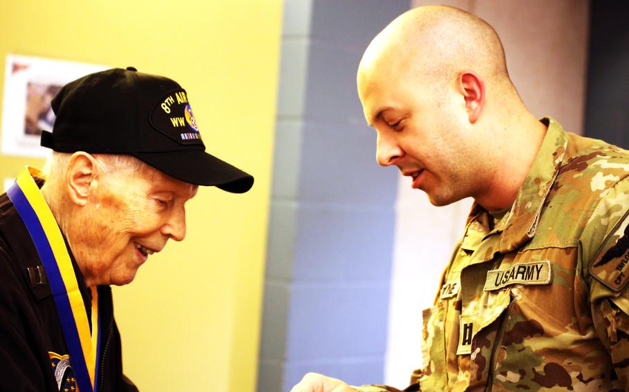 Capt. Taylor Payne, commander of Headquarters and Headquarters Company, 1st Battalion, 168th General Support Aviation presents a coin to Capt. Dick Nelms, World War II pilot during a presentation of the Knight of the Honorable Order of Saint Michael award at the Washington Army National Guard Aviation Readiness Center, Joint Base Lewis-McChord, Wash., on Sunday, March, 3, 2024.