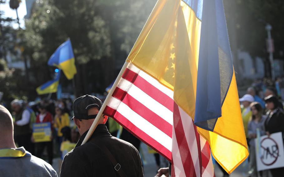 A California resident walks with the American and Ukrainian flags at a rally in support of Ukraine in Sacramento, Calif., on March 6, 2022. About 65% of Americans have a positive view of Ukraine and are confident in the leadership of its president, Volodymyr Zelenskyy, a recent Pew poll found.
