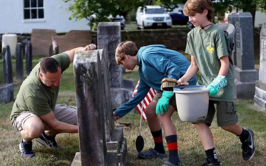 Volunteers clean the headstones of veterans at Rosemont Cemetery in Delaware Township, N.J., on Aug. 21, 2022.