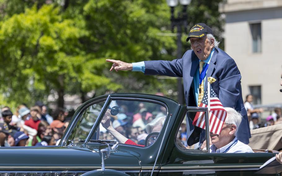 A veteran wearing his WWII cap waves.