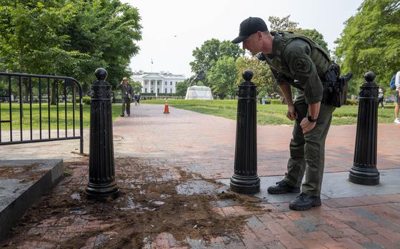 FILE - A U.S. Park Police officer inspects a security barrier for damage in Lafayette Square park near the White House, May 23, 2023, in Washington. A Missouri man pleaded guilty Monday, May 13, 2024, to crashing a rented truck into White House barriers last year. Sai Varshith Kandula drove a large U-Haul truck onto a sidewalk, sending pedestrians running for safety, before ramming it into metal bollard barriers that prevent vehicles from entering Lafayette Square. (AP Photo/Alex Brandon, File)