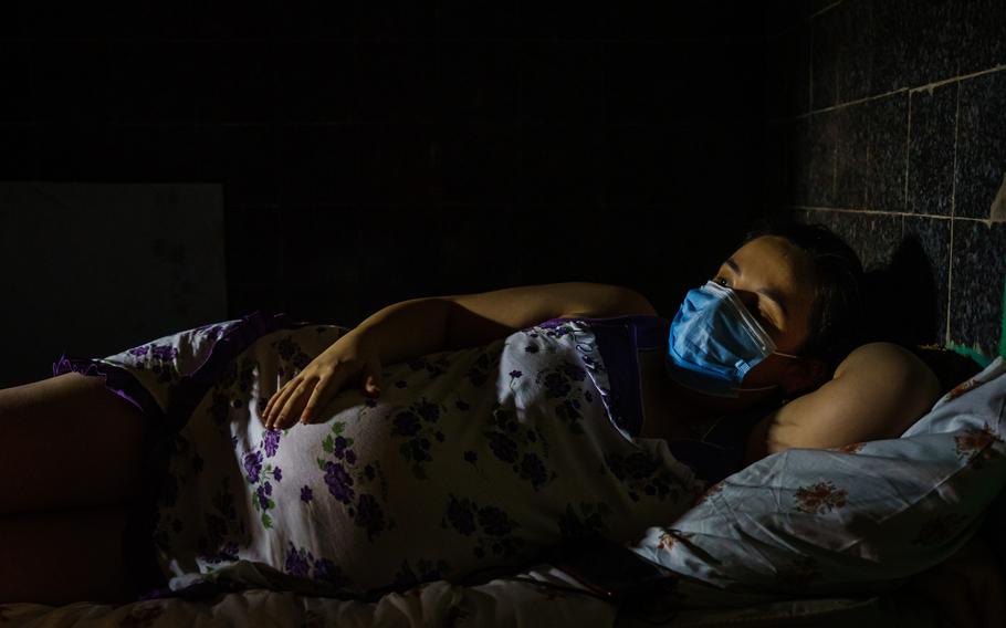 Kate Shepel lays on her side in a dark shelter after a maternity ward moved its patients underground a safer place because its exterior had been bombarded, in Kharkiv, Ukraine, on March 25, 2022.