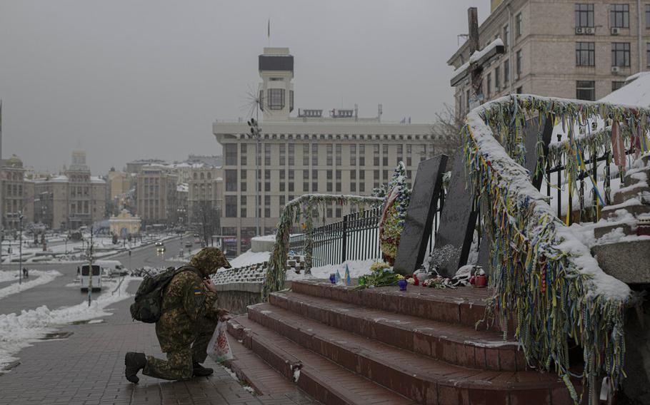 A Ukrainian serviceman kneels in front of a memorial dedicated to people who died in clashes with security forces in Kyiv, Ukraine, on Monday, Nov. 21, 2022. 