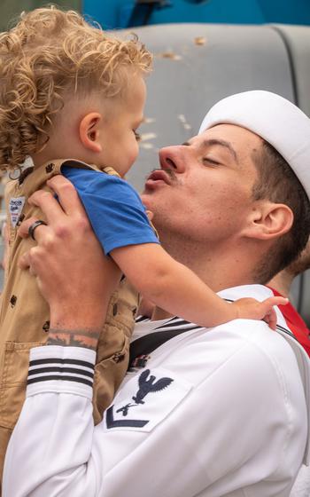 A sailor holds up his daughter.