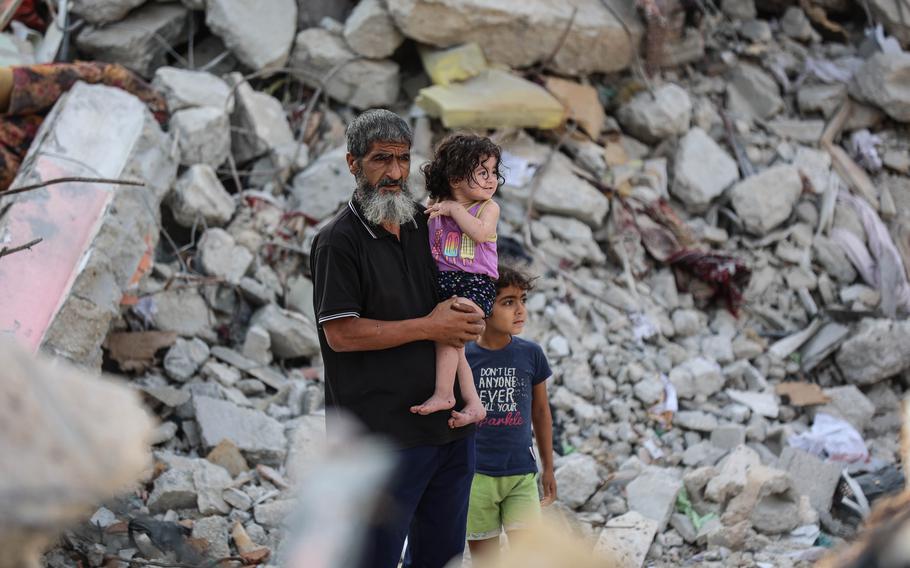 A man holds his granddaughter amid rubble in Khan Younis in Gaza on Oct. 30