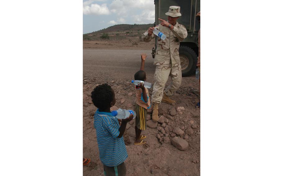 Staff Sgt. Arthur Dodds, 35, an Army reservist from Hopedale, Ohio, hands out water to Djiboutian children on a road near Djibouti City that he helped repair. U.S. service members stationed at Camp Lemonier in Djibouti say they hope such civil affairs projects give Djiboutians a good impression of Americans and make them less likely to support terrorists in the Horn of Africa.