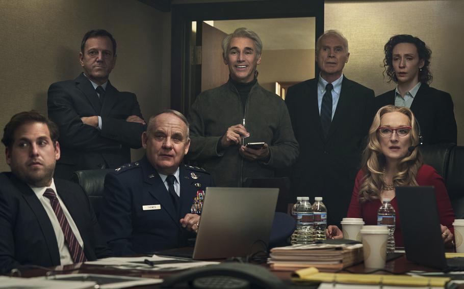 Mark Rylance, standing center, with main cast members, seated from left, Jonah Hill, Paul Guilfoyle and Meryl Streep in a scene from “Don’t Look Up.” Rylance portrays tech billionaire Peter Isherwell. 