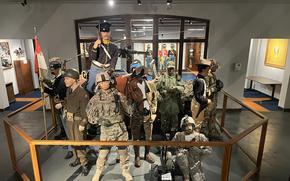Military uniforms are on display in a museum.