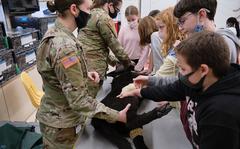 Army Sgt. Jordan Tubbs, left, and Cpl. Madison Green of Camp Zama show students the latest technology in treating animal wounds during a STEAM event at Naval Air Facility Atsugi, Japan, May 27, 2021. 