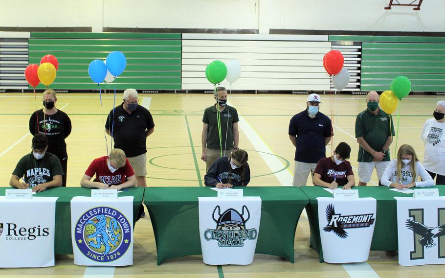 Naples High School seniors Francesco Buanne, Tyler Lambertson, Ariana Coats, Dominic Younger and Roxanne Sasse, from left, commit to various colleges and universities at the school in Italy, May 18, 2021, as their coaches look on.