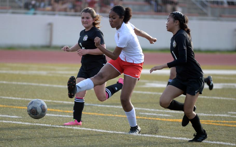 Nile C. Kinnick's Alyssa Staples boots the ball between Matthew C. Perry's Victoria Theberge and Elieza Cuaco during Friday's DODEA-Japan girls soccer match. The Red Devils won 2-1.