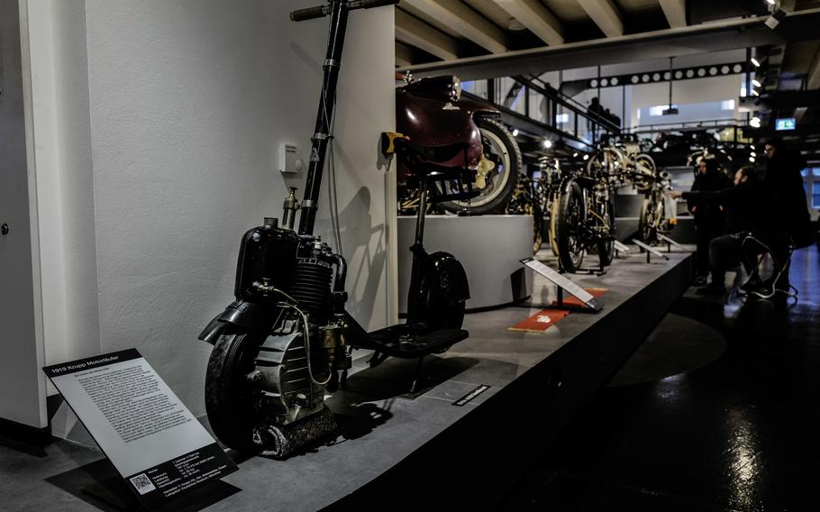 A 1919 Krupp Motorrunner scooter is on display as visitors look at the 1902 Clement motorcycle at the German Motorcycle Museum in Neckarsulm, Germany, Jan. 21, 2024. The Clement was the first motorcycle in the world with a V-engine, leading the way for the popular Harley-Davidson engines of today.